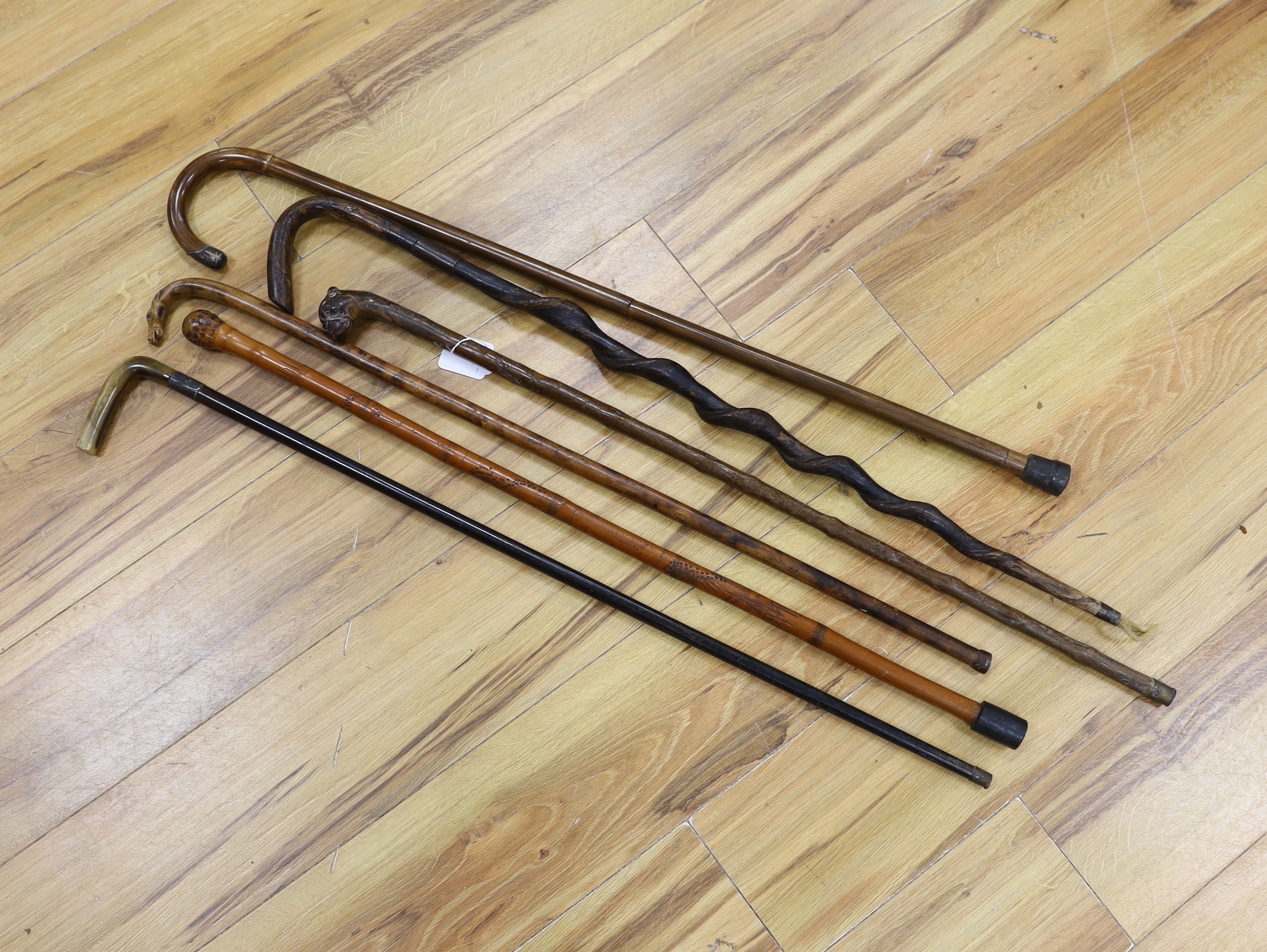 Six assorted walking sticks: a spiral carved cane, a silver mounted, a horn handled, a carved dog handled and a carved horse handled walking stick